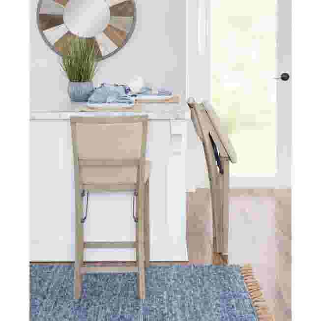 Grey wash folding bar stool in a kitchen setting with one stool folded