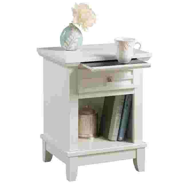 White nightstand with drawer and open shelf, holding a vase and a mug.