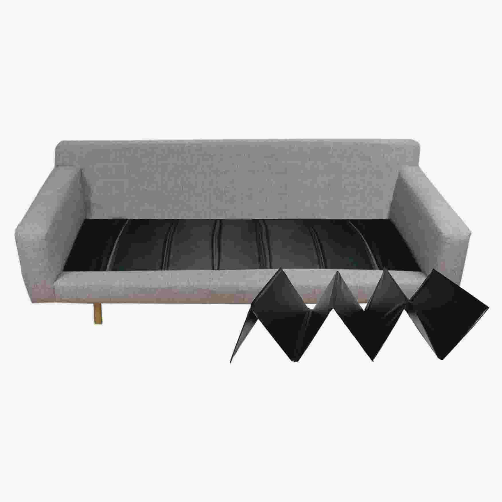 A gray sofa with a black sofa cushion support placed in front of it.